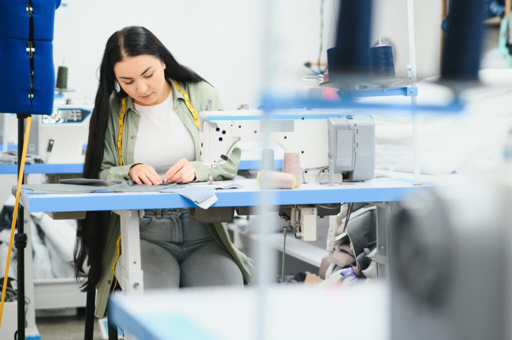 Portrait of a beautiful seamstress carrying a tape measure to make wholesale bodysuits in a textile factory.