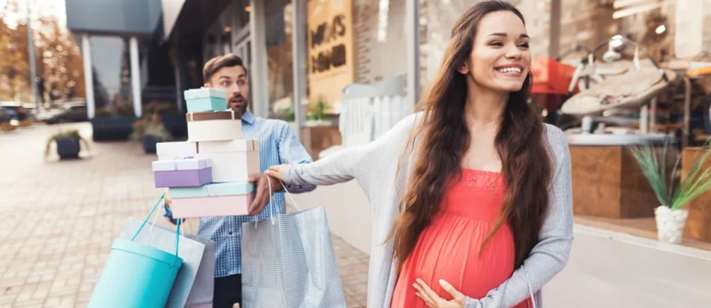 Beautiful young pregnant mother choosing and buying colorful clothes and appliances